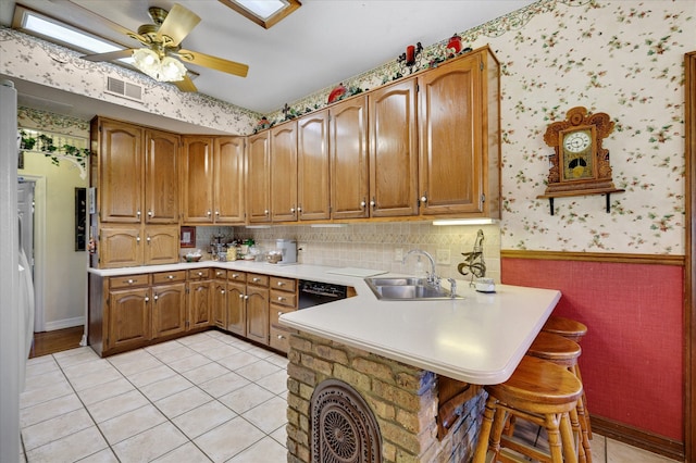 kitchen featuring sink, kitchen peninsula, backsplash, light tile patterned floors, and ceiling fan