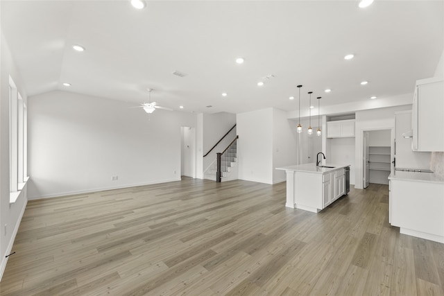 unfurnished living room featuring sink, light hardwood / wood-style flooring, ceiling fan, and vaulted ceiling