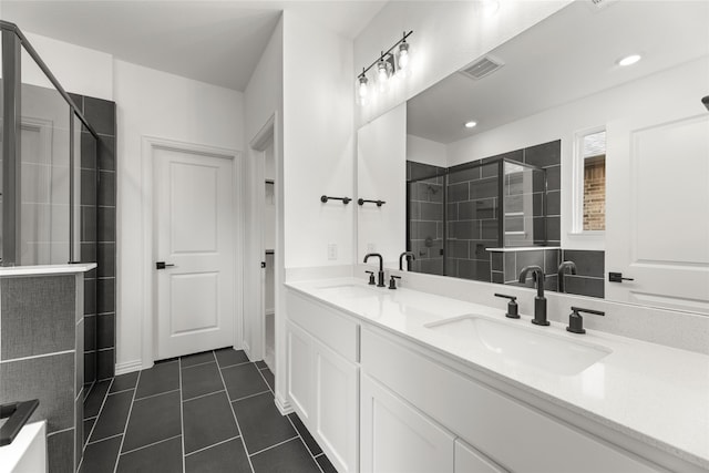 bathroom featuring tiled shower, vanity, and tile patterned flooring