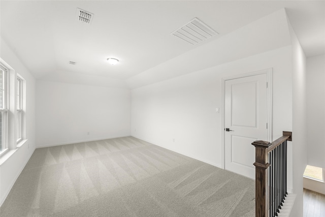 empty room featuring vaulted ceiling and light carpet