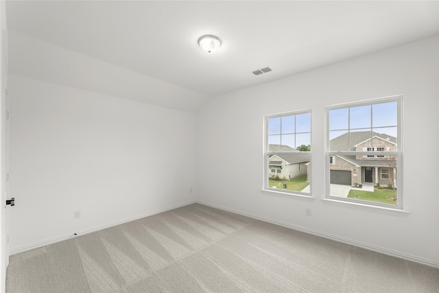 carpeted spare room featuring vaulted ceiling