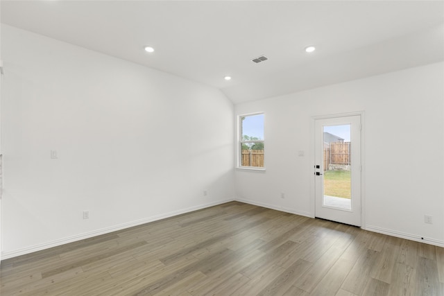 spare room with lofted ceiling and light wood-type flooring