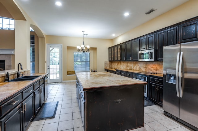 kitchen with pendant lighting, sink, appliances with stainless steel finishes, a notable chandelier, and a kitchen island