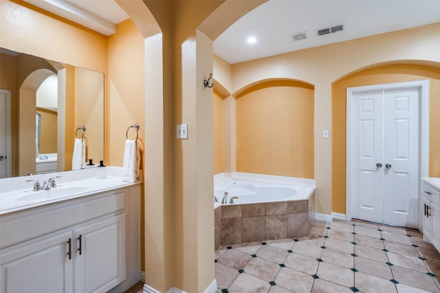 bathroom featuring vanity and a relaxing tiled tub