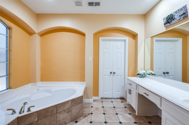 bathroom featuring tile patterned flooring, vanity, and tiled tub