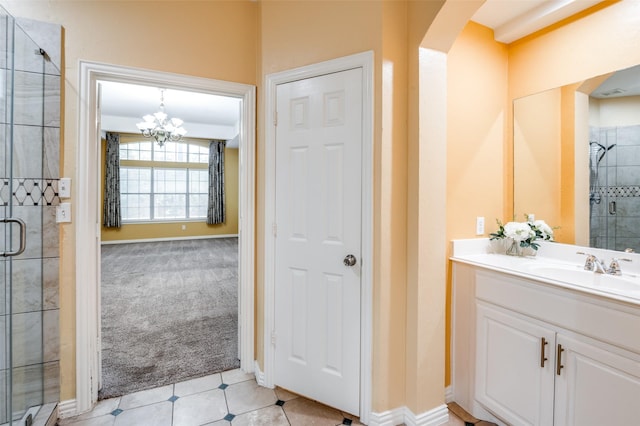 bathroom featuring tile patterned floors, vanity, a shower with shower door, and an inviting chandelier