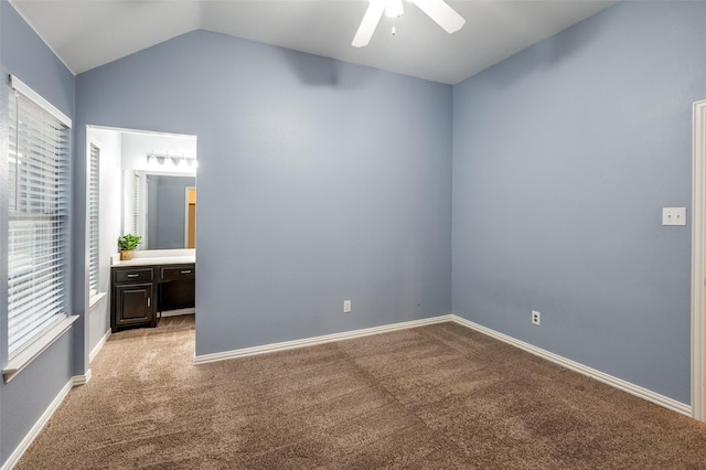 unfurnished bedroom with ceiling fan, light colored carpet, lofted ceiling, and ensuite bath