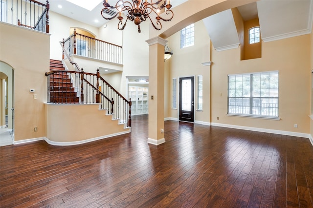 entrance foyer with plenty of natural light, a towering ceiling, dark wood-type flooring, and ornamental molding