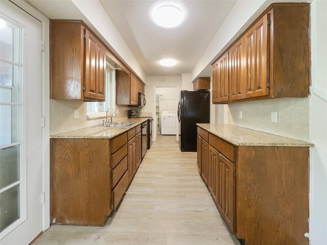 kitchen featuring sink, black fridge, tasteful backsplash, and light wood-type flooring