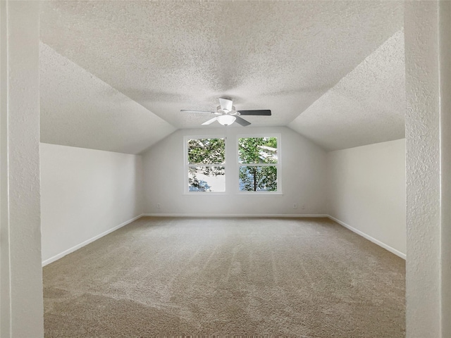 bonus room featuring lofted ceiling, a textured ceiling, ceiling fan, carpet floors, and baseboards