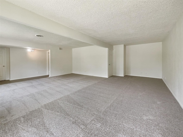 spare room featuring light carpet, a textured ceiling, and baseboards