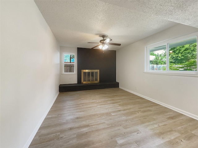 unfurnished living room featuring a wealth of natural light, light wood-type flooring, and a fireplace