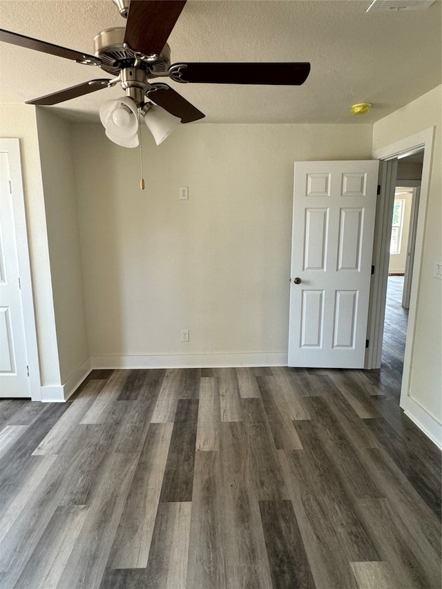 empty room with a textured ceiling, dark hardwood / wood-style floors, and ceiling fan