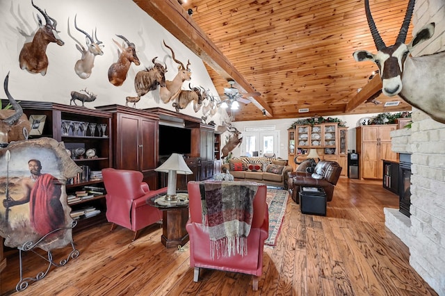 living room with beamed ceiling, wood ceiling, a fireplace, ceiling fan, and wood-type flooring