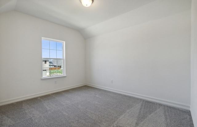 carpeted spare room featuring lofted ceiling