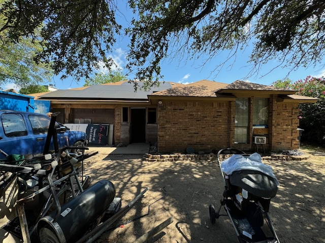 rear view of house featuring solar panels and a garage