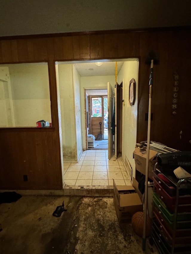 hallway featuring light tile patterned floors and wood walls