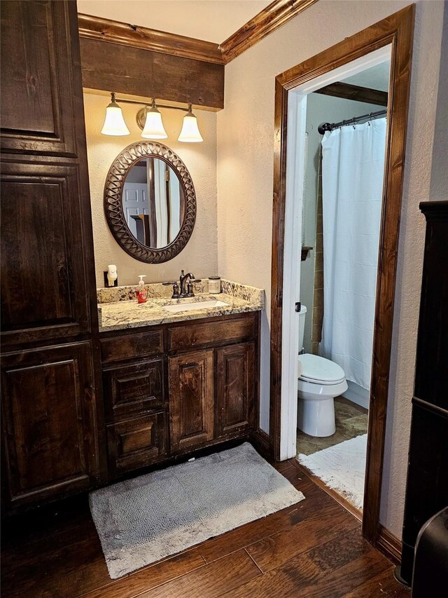 bathroom with curtained shower, hardwood / wood-style flooring, ornamental molding, vanity, and toilet