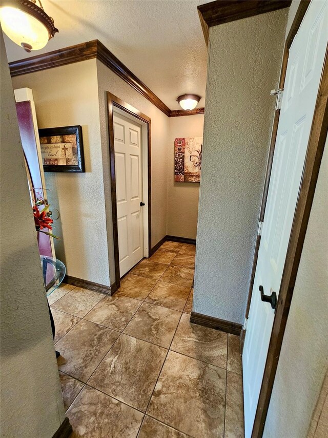 hallway featuring crown molding, tile patterned floors, and a textured ceiling