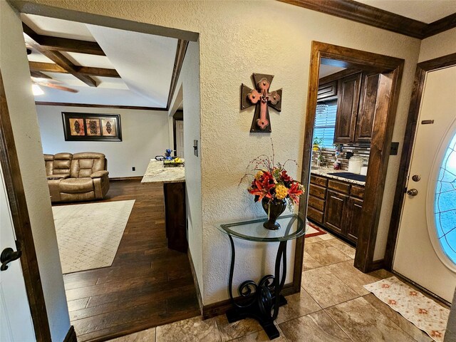 entryway with coffered ceiling, ornamental molding, beamed ceiling, and light wood-type flooring