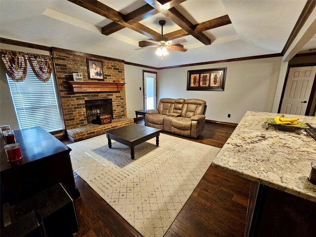 living room with ornamental molding, a brick fireplace, coffered ceiling, and dark hardwood / wood-style floors