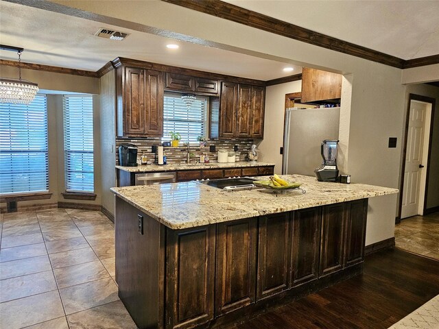 kitchen featuring ornamental molding, appliances with stainless steel finishes, light stone counters, and decorative light fixtures