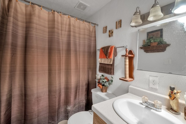 bathroom featuring toilet, vanity, and a textured ceiling