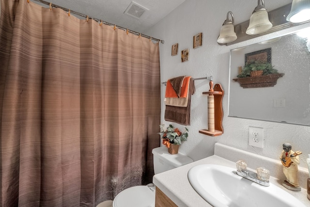 full bathroom featuring vanity, a shower with shower curtain, visible vents, toilet, and a textured wall