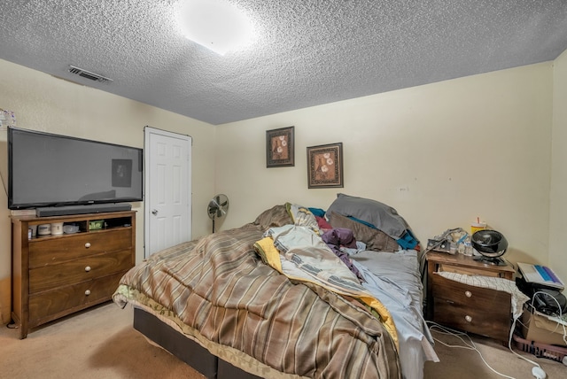 bedroom featuring visible vents, light colored carpet, and a textured ceiling