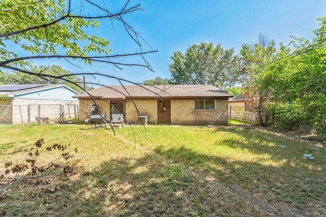 rear view of house featuring a yard and fence