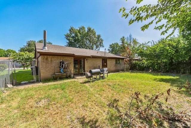 rear view of house with brick siding, a lawn, and fence