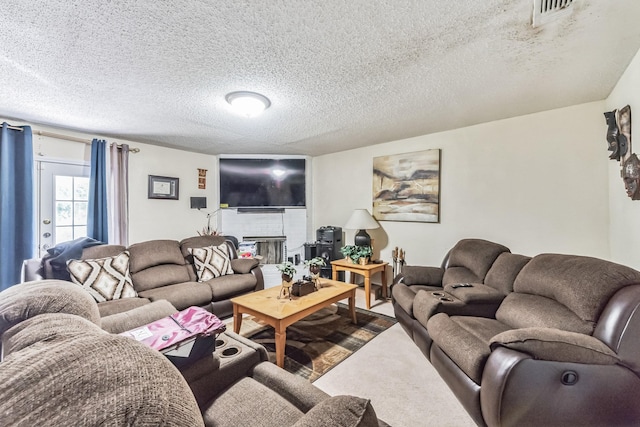 living room featuring visible vents, a fireplace, a textured ceiling, and wood finished floors