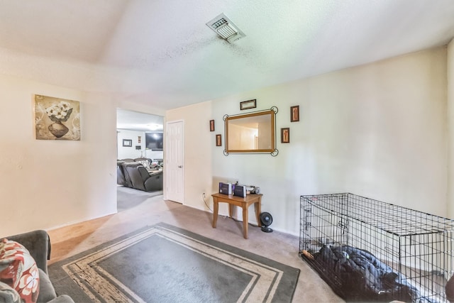 living area featuring visible vents, carpet floors, and a textured ceiling