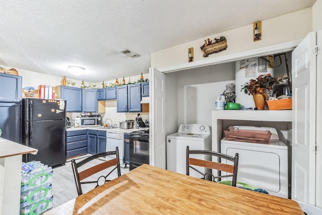 kitchen with visible vents, blue cabinetry, black appliances, light countertops, and independent washer and dryer