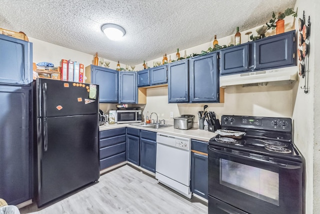 kitchen featuring light wood finished floors, under cabinet range hood, light countertops, black appliances, and a sink
