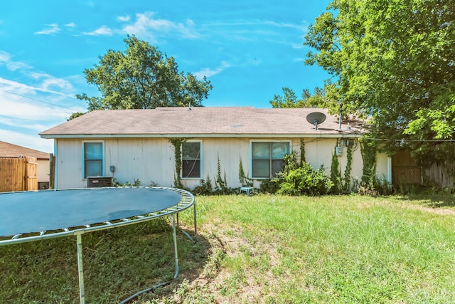 back of house with a trampoline and a yard