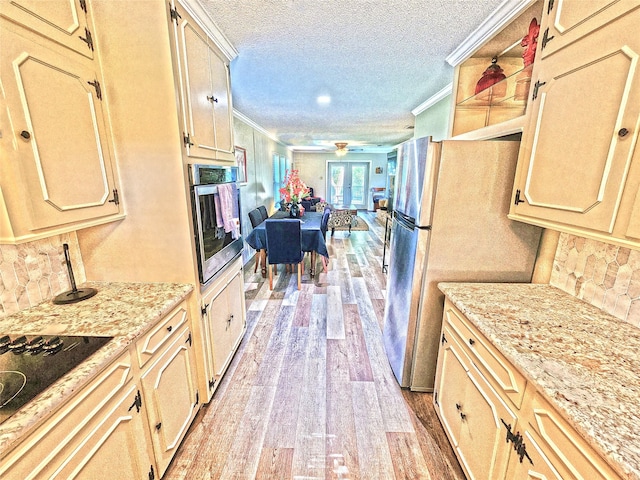 kitchen with light hardwood / wood-style flooring, stainless steel appliances, backsplash, crown molding, and a textured ceiling