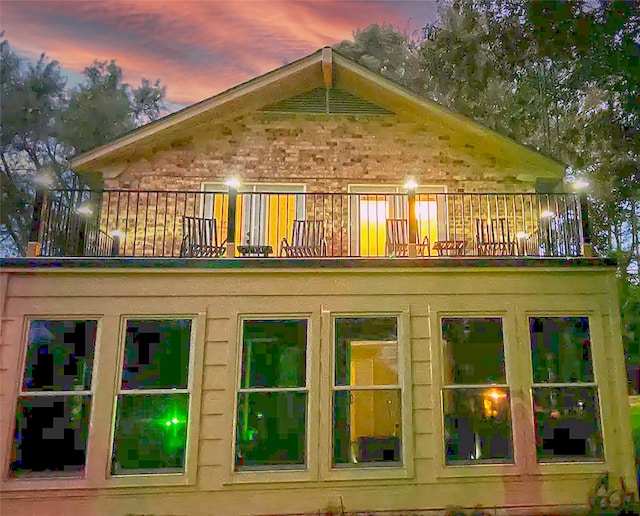 back house at dusk featuring a balcony