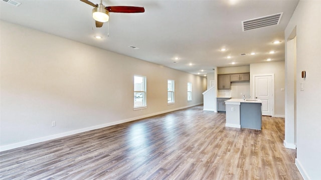 unfurnished living room with visible vents, light wood-style flooring, and baseboards