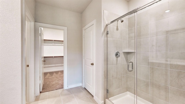 full bath with a spacious closet, a shower stall, and tile patterned floors