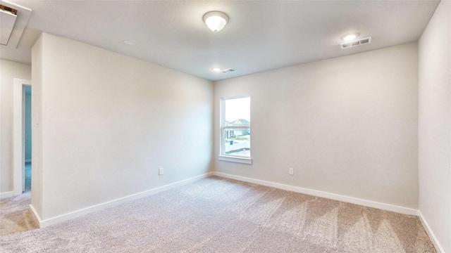 unfurnished room featuring attic access, light colored carpet, visible vents, and baseboards