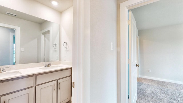 bathroom featuring double vanity, a sink, visible vents, and baseboards