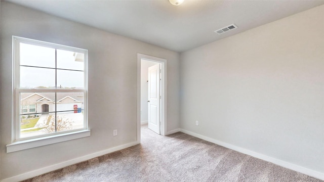 carpeted empty room featuring visible vents and baseboards