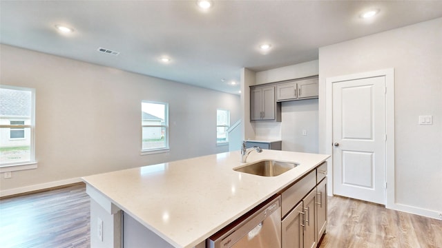 kitchen featuring sink, an island with sink, stainless steel dishwasher, and plenty of natural light