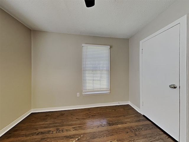 unfurnished room with dark wood-style floors, a textured ceiling, and baseboards