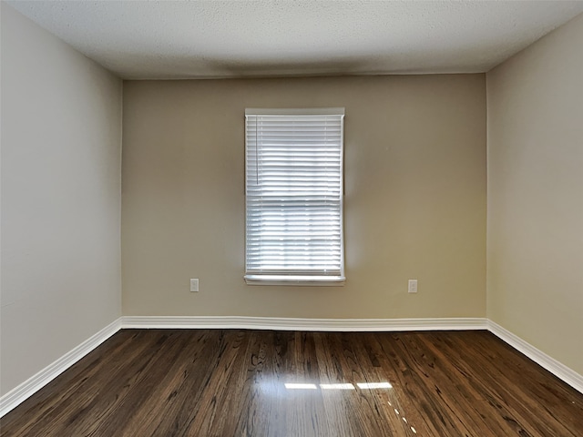 unfurnished room with dark wood finished floors, a textured ceiling, and baseboards