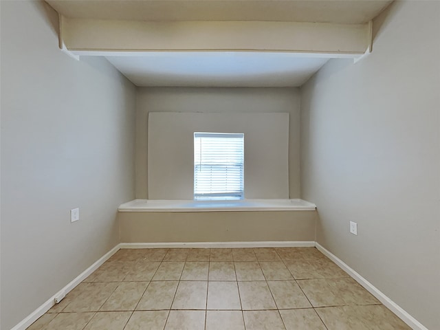 empty room with baseboards and light tile patterned floors