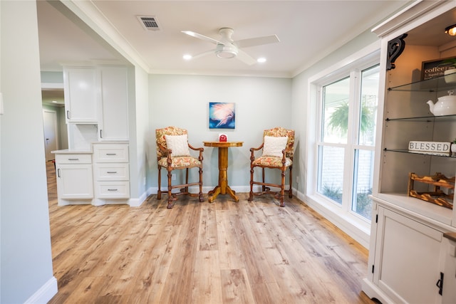 living area with ceiling fan, crown molding, and light hardwood / wood-style flooring