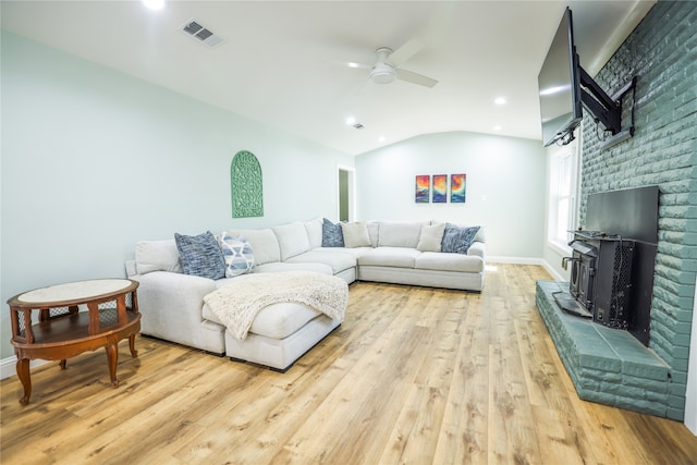 living room featuring vaulted ceiling, ceiling fan, light hardwood / wood-style flooring, and a brick fireplace