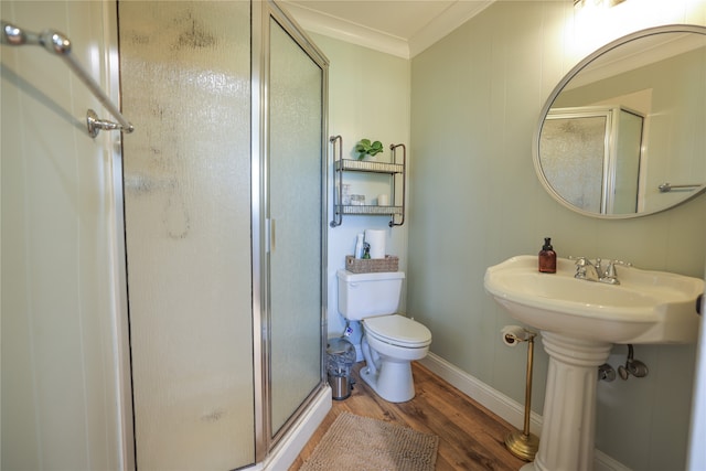 bathroom with a shower with shower door, hardwood / wood-style floors, toilet, and crown molding